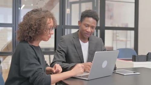 Colleagues Collaborating on Laptop in Modern Office