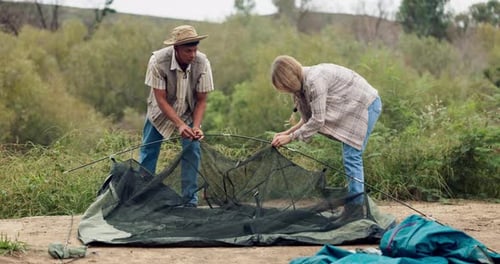 Adults Setting Up Tent Together in Rural Area