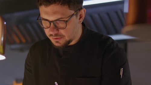 Chef Writing Order Ticket while Managing Restaurant Kitchen Service