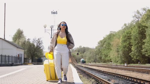 Stylish Woman Walking with Suitcase on Train Platform