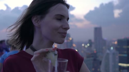 Young, Happy Woman Drinking Cocktail and Admire View Standing on Terrace In