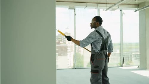 Afroamerikanischer Maler malt eine Wand im Haus