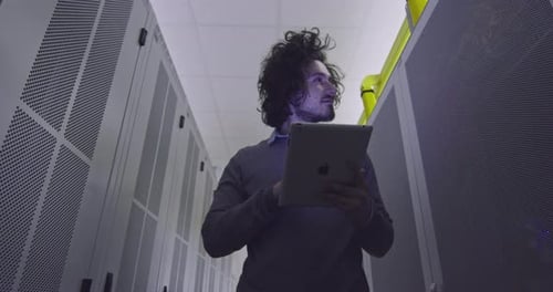Young Adult Inspecting Servers with Tablet
