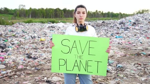 Woman Holds Save the Planet Sign in Landfill