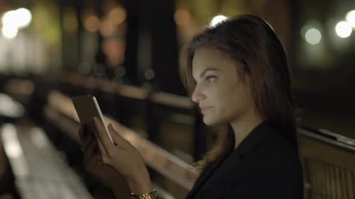 Young Woman Using Tablet Computer In The Park At Night