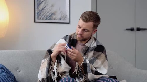 Man Checking Pulse Oximeter While Sitting on Couch
