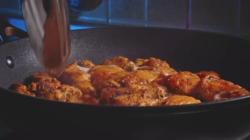 Cooking And Flipping Spicy Marinated Chicken Breast In A Pan Using Tongs. close up
