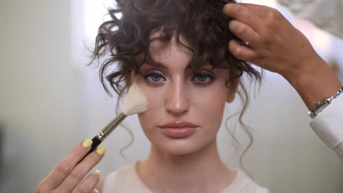 Closeup Portrait of Young Gorgeous Woman Looking at Camera While Makeup Artist and Hairdresser Final