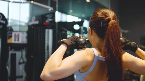 Back view of Asian women doing exercises in fitness, exercises to strengthen muscles and strength