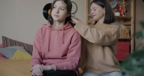 Woman brushing girl's hair in brightly lit home