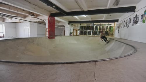 Professional Skateboarder Practicing Skills at Skatepark Bowl