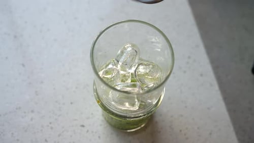 Closeup Top View of Unrecognizable Bartender Male Pouring Alcohol to Glass with Mashed Kiwi and Ice