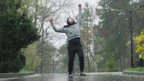 Man Celebrates Rainy Run in Park