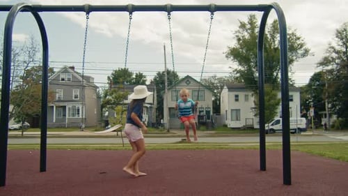 Two Children Play on Swings in Urban Park