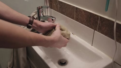 Person Washing Clothing in Bathroom Sink