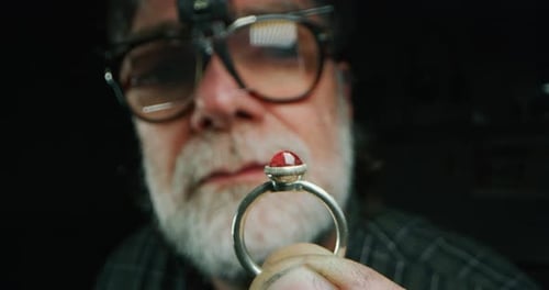 Slow motion of experienced goldsmith controlling a quality of just finished handmade jewelry ring