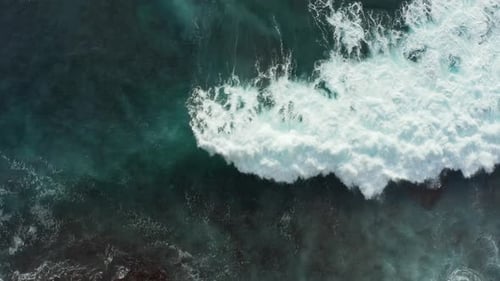 Beautiful aerial top down view of clear turquoise blue ocean water covering reef rocks. Waves crashi