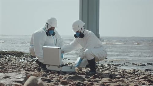 Dos ecologistas con overoles discuten muestras de agua contaminada