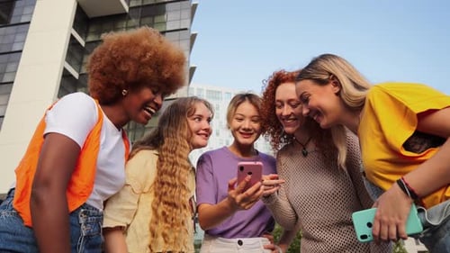 Gruppe glücklicher junger Frauen, die ihren Smartphones zuschauen und süchtig nach Social Media-Apps sind und Spaß haben
