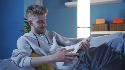 Man Reading Book on Couch Indoors