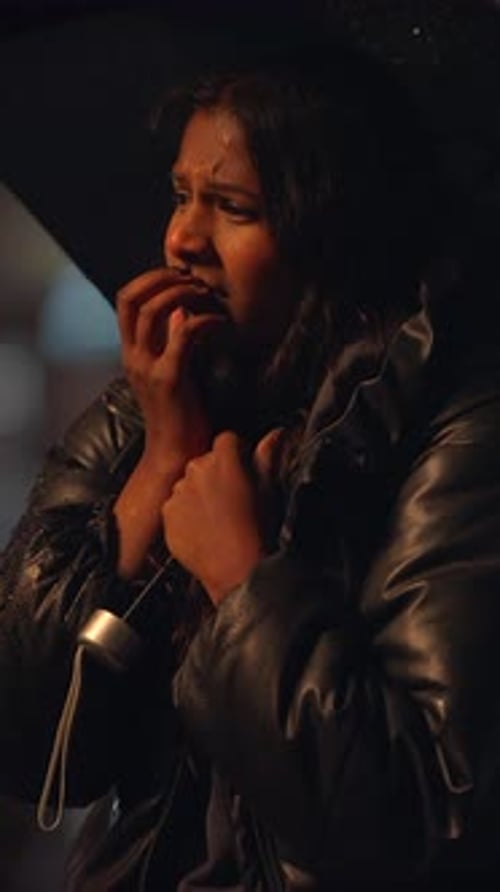 Anxious Woman Huddles in the Rain at Night