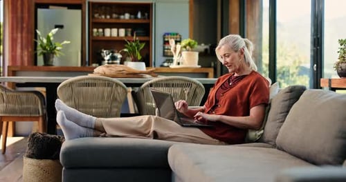 Senior Woman Relaxing on Couch Using Laptop