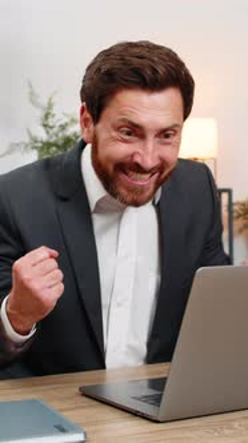 Middleaged Businessman Celebrates Profit Green Chart on Laptop Shouts Hooray After Online Game Win