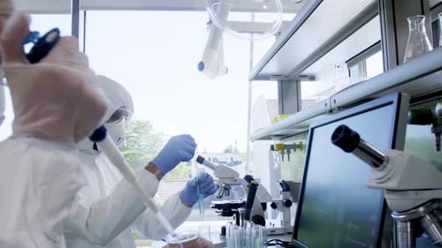 Scientists in Protection Suits and Masks Working in Research Lab Using Laboratory Equipment