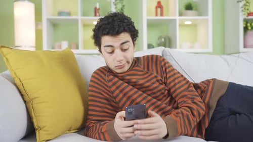 Teen Lying on Couch Using Smartphone Indoors