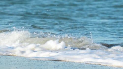 A powerful wave crashes on the shore, its white foam spraying in the air.