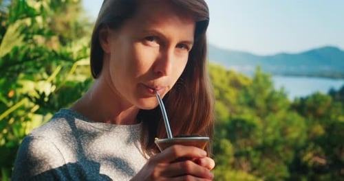 Mate drink outdoor. Portrait of the young caucasian woman drinking mate from traditional cup