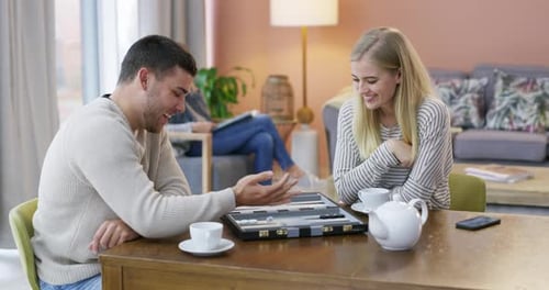 Woman, board game or man playing backgammon in living room for fun, strategy or bonding at home