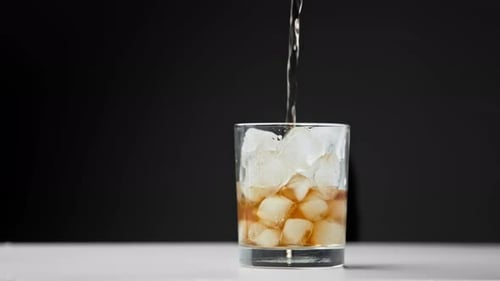 Brown Liquid Poured into Glass with Ice