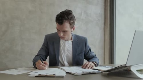 Young Man Reviews Project Charts in Modern Office