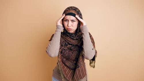 Woman Wearing Hijab Rubbing Temples in Discomfort