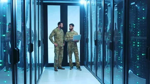 Two Soldiers Analyze a Laptop in a Hightech Data Center