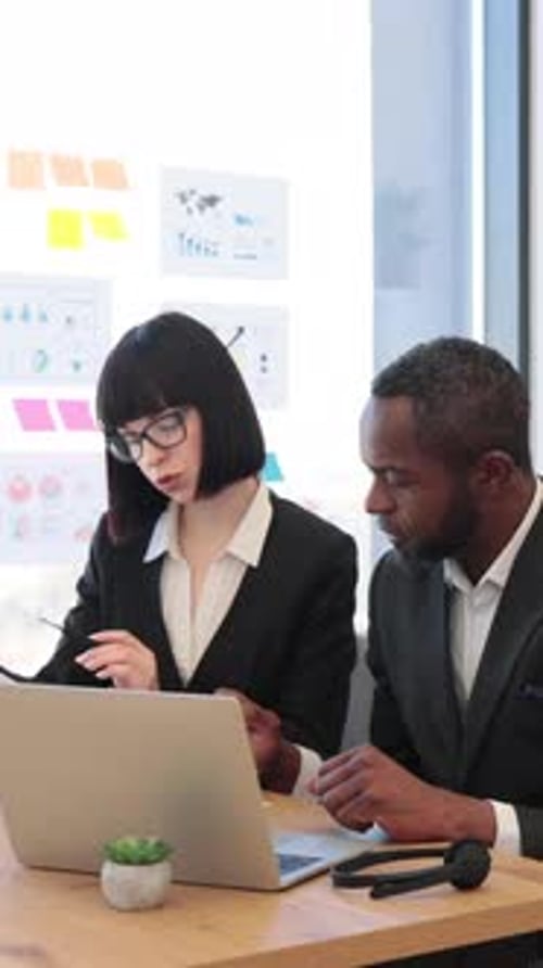 Professionals Work Together at Desk in Modern Office