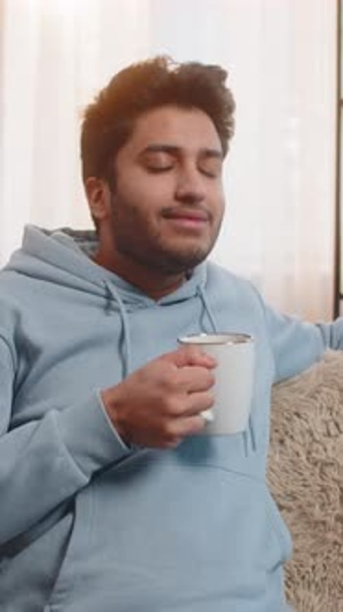 Man Relaxing Indoors, Enjoying a Warm Drink