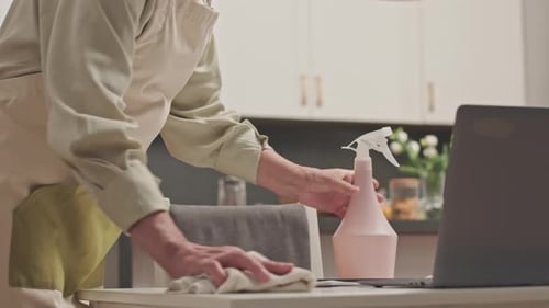 Person Cleaning Table with Spray and Cloth
