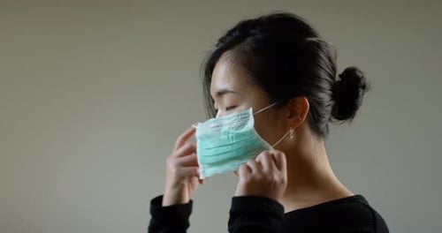 Asian Woman Putting On Face Mask In Slow Motion B