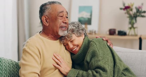 Senior Couple Cuddling Affectionately on Sofa at Home