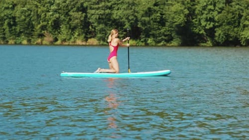 Serious Young Attractive Woman Paddle on Their Knees Rowing on Lake Surfboard Sport Surfer Water