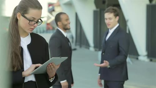 Business Woman Standing in the Street While Two Businessmen Shaking Hands