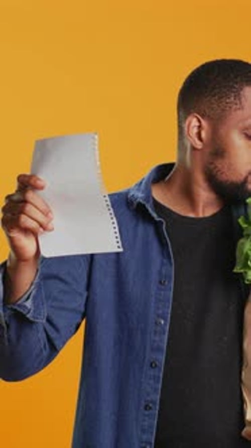 Vertical Video Young Adult Looking Over His Grocery Shopping List and Checking His Produce