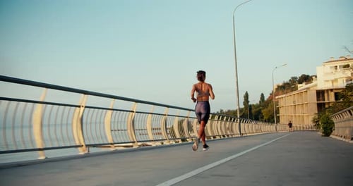 A Girl in a Sports Summer Uniform Runs Along the Bridge Morning Run in the City