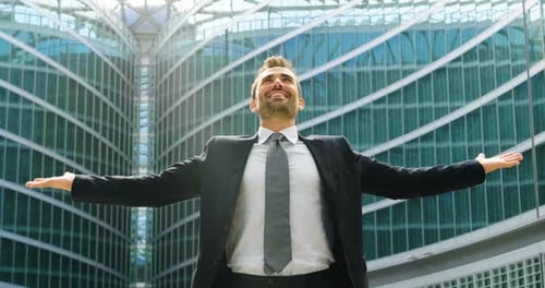 Smiling Businessman Celebrates Success Near Office Building