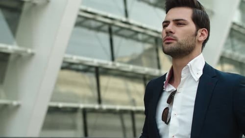 Confident businessman in stylish suit checks time in the city outdoors
