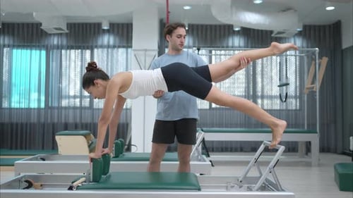 Woman Exercising on Pilates Machine with Trainer