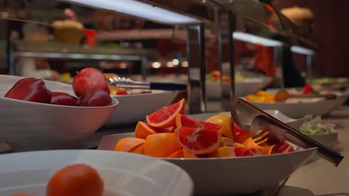 Niedrige Buffetschalen mit Zitrusfrüchten und Äpfeln unter Glasschutz