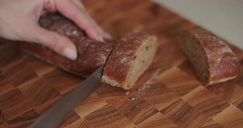 Hands Slice Delicious Bread Loaf on Wooden Board